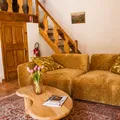 Rustic sitting area with brown sofa, wooden coffee table, bouquet of flowers and stairs in the background.