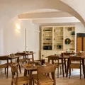 Rustic dining room with wooden tables and chairs under a white vaulted ceiling.