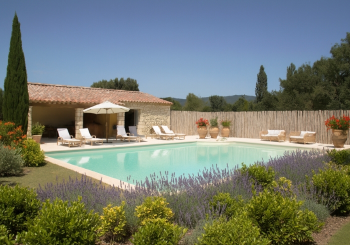 Buffet salé de mariage devant la piscine extérieure du Domaine de la Vivande, pool house en pierre, chaises longues beiges, grande piscine entourée de lavande