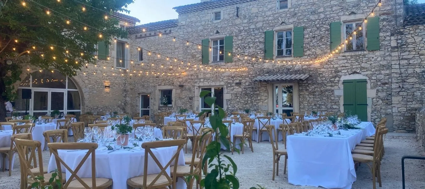 Dîner de mariage en soirée dans la cour intimiste de la Bastide, tables rondes dressées avec nappes blanches