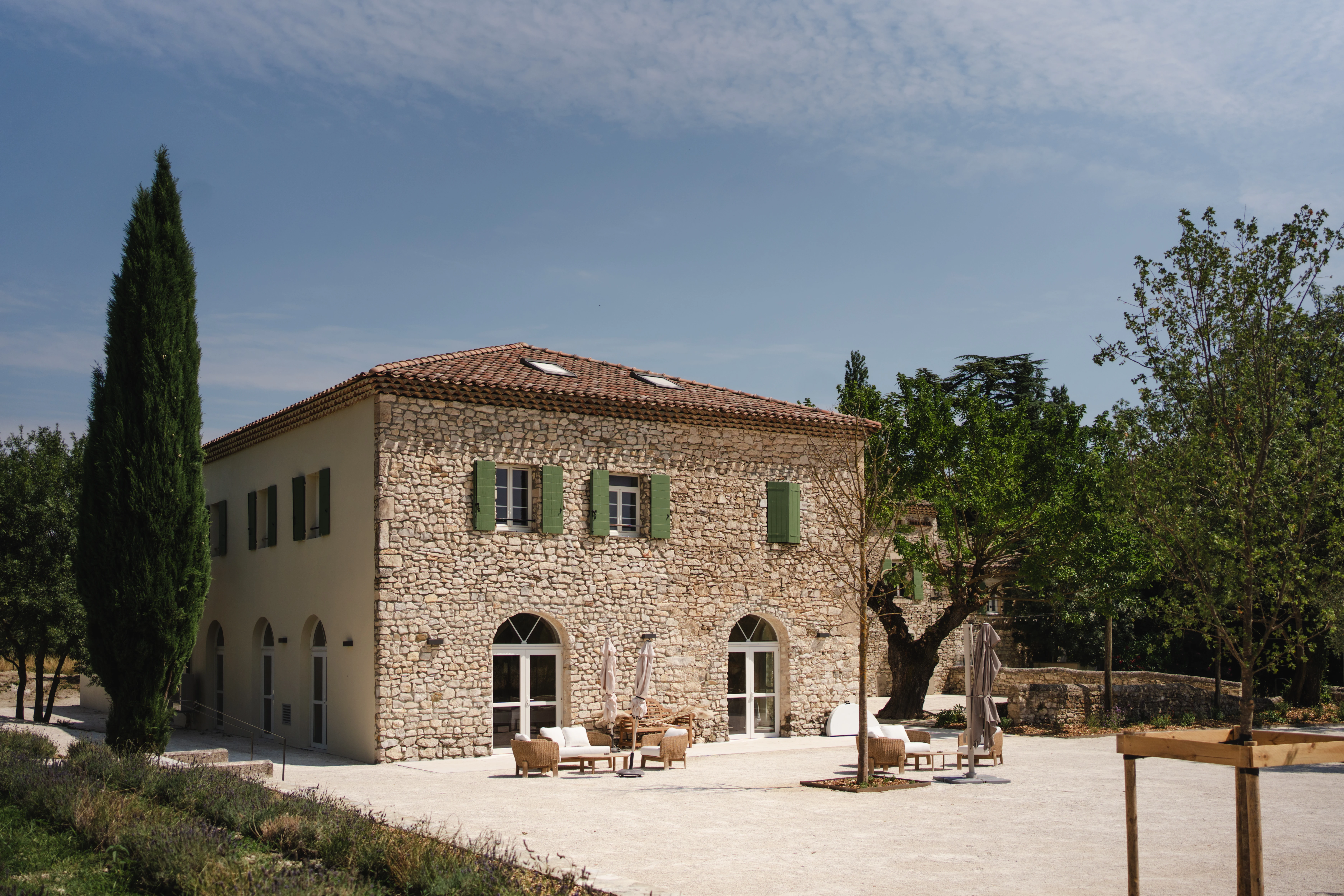 Extérieur du Domaine de la Vivande à La Marsanne, mas provençal en pierre, fontaine octogonale centrale, bassin entouré de lavande et de pots en terre cuite