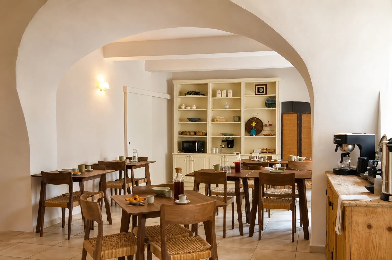 The Olivade Room for breakfast, vaulted interior, Provencal or country house style, exposed stone walls, dark rustic wood furniture, tables for two or four people, buffets with fruit and flower trays