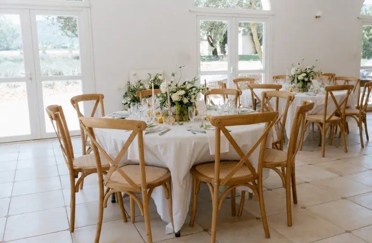 La Salle de la Bastide reception room, vaulted interior, light beige walls, wedding or country event decor, round tables set, light wood cross chairs