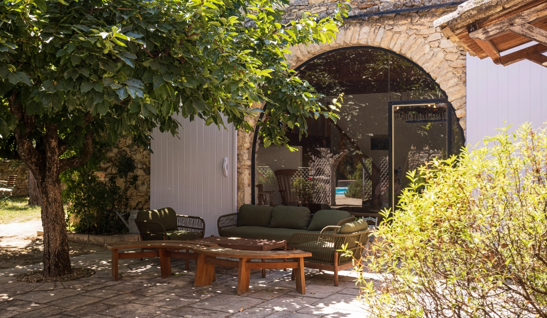 Façade en pierre du Mas du Domaine de la Vivande sous la lumière dorée, entourée d'oliviers