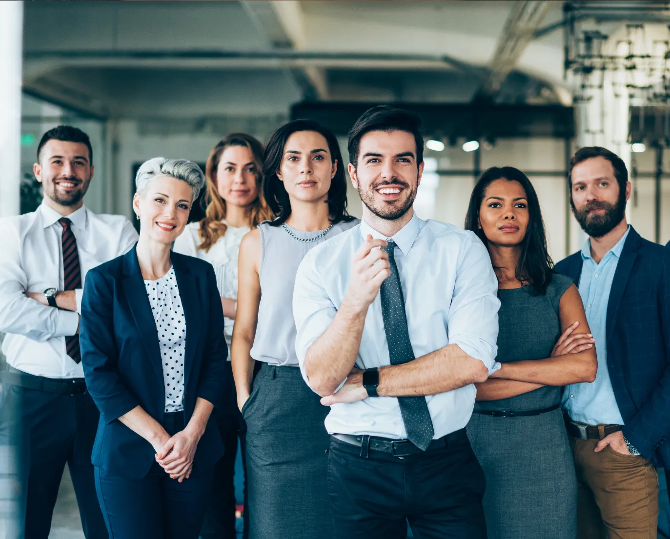Diverse group of seven business professionals standing confidently in an office setting.