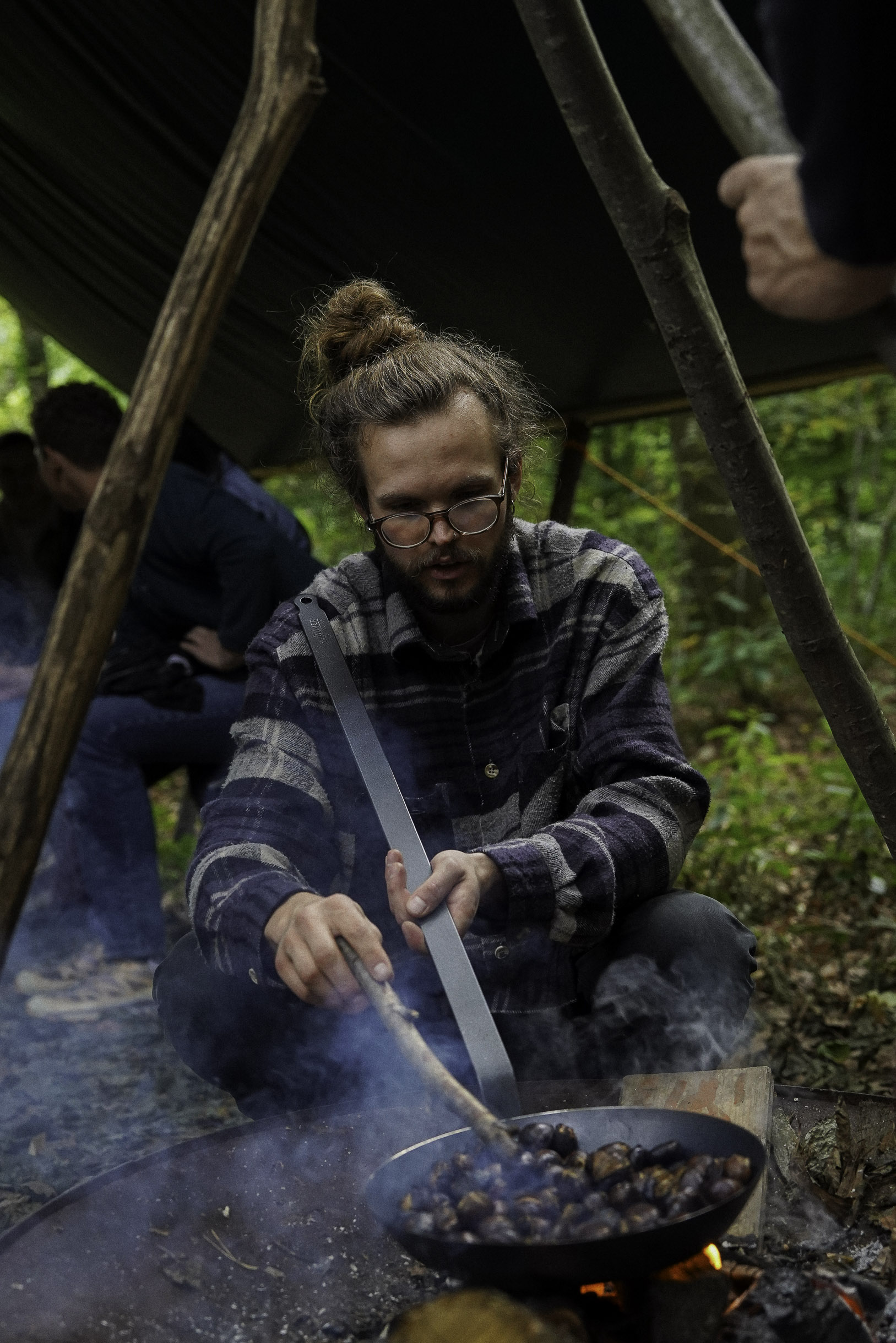 Een man roostert tamme kastanjes in een houtvuur