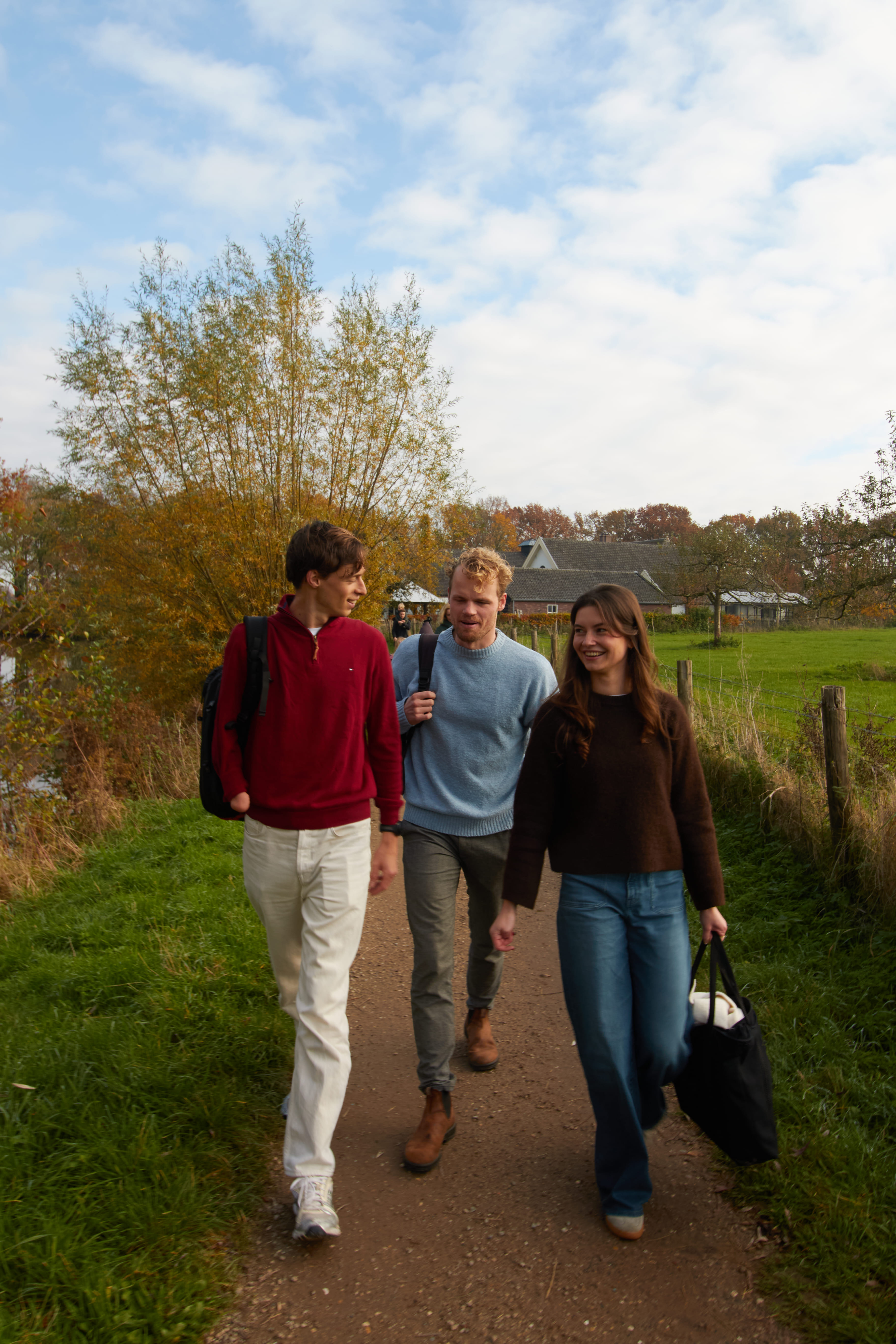 The three employees of Brainwave walking and chatting on a dirt path in a rural area with green grass and trees.