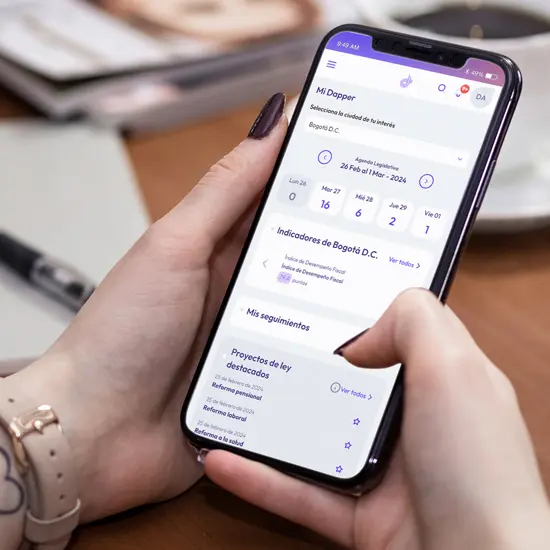 Person holding a smartphone displaying a Spanish app screen with legislative session dates and Bogotá D.C. indicators.