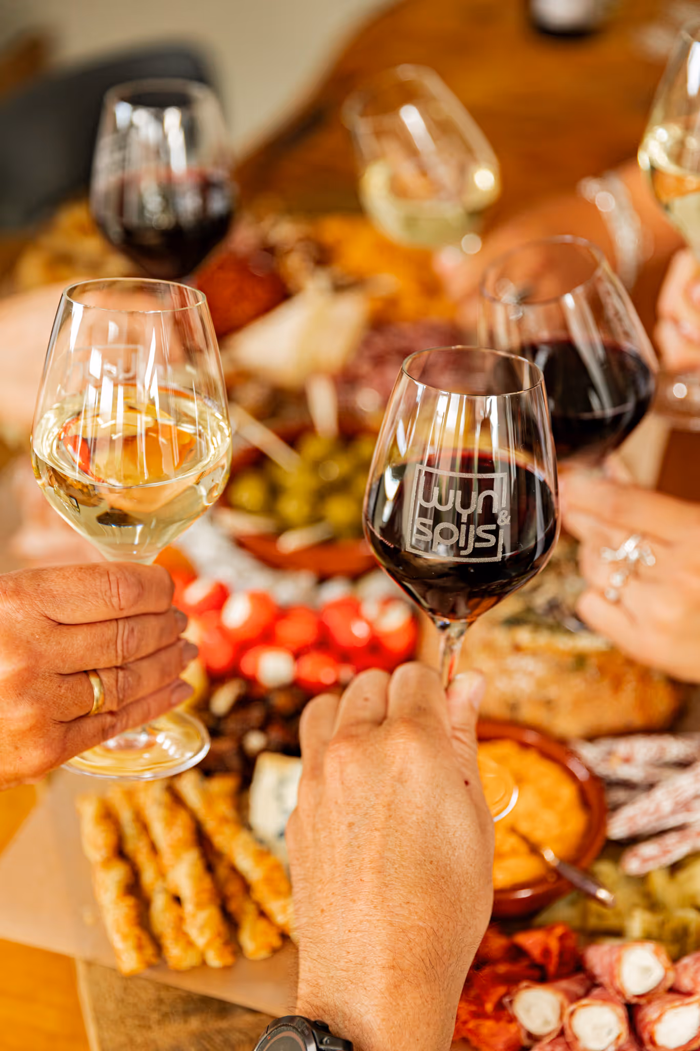 A picture of people sitting around a charcuterie board cheersing with glasses of wine