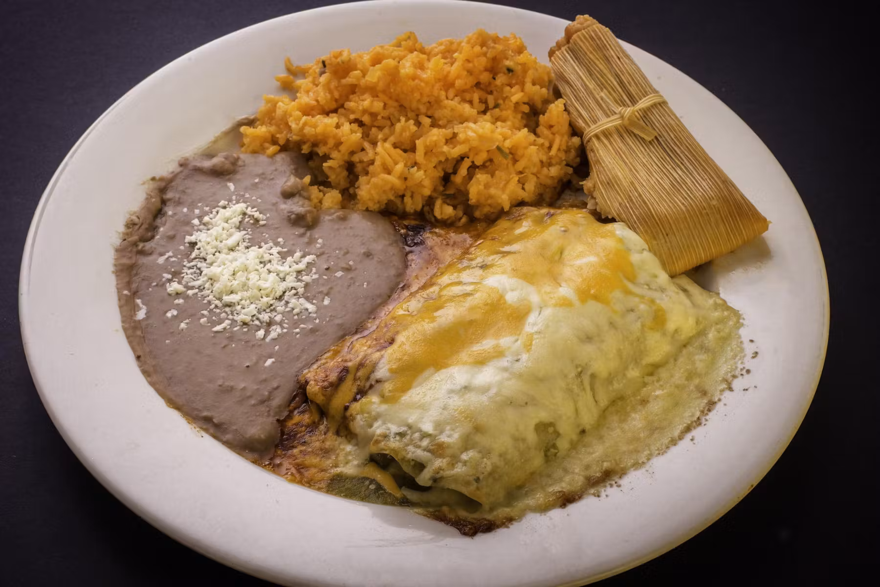 Plate of tamales served with rice and beans.