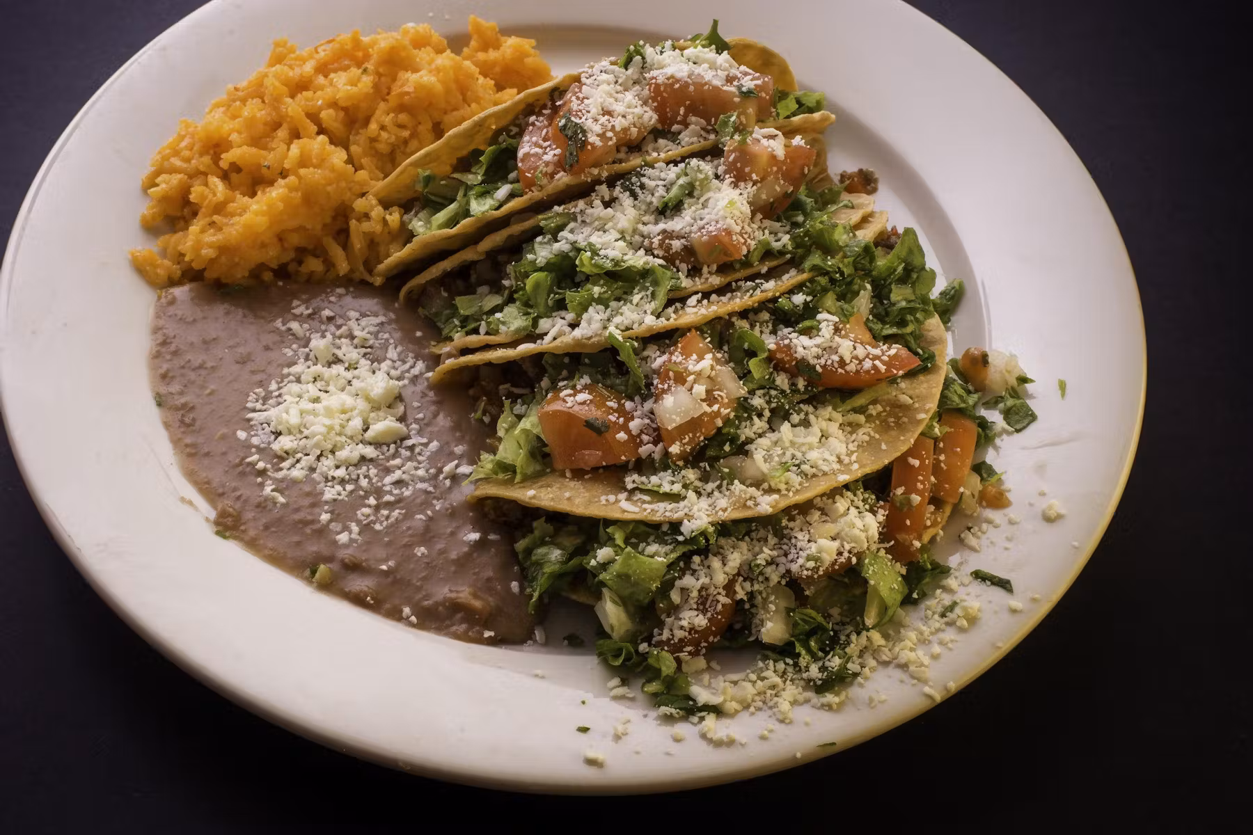 Plate of tacos served with rice and beans.