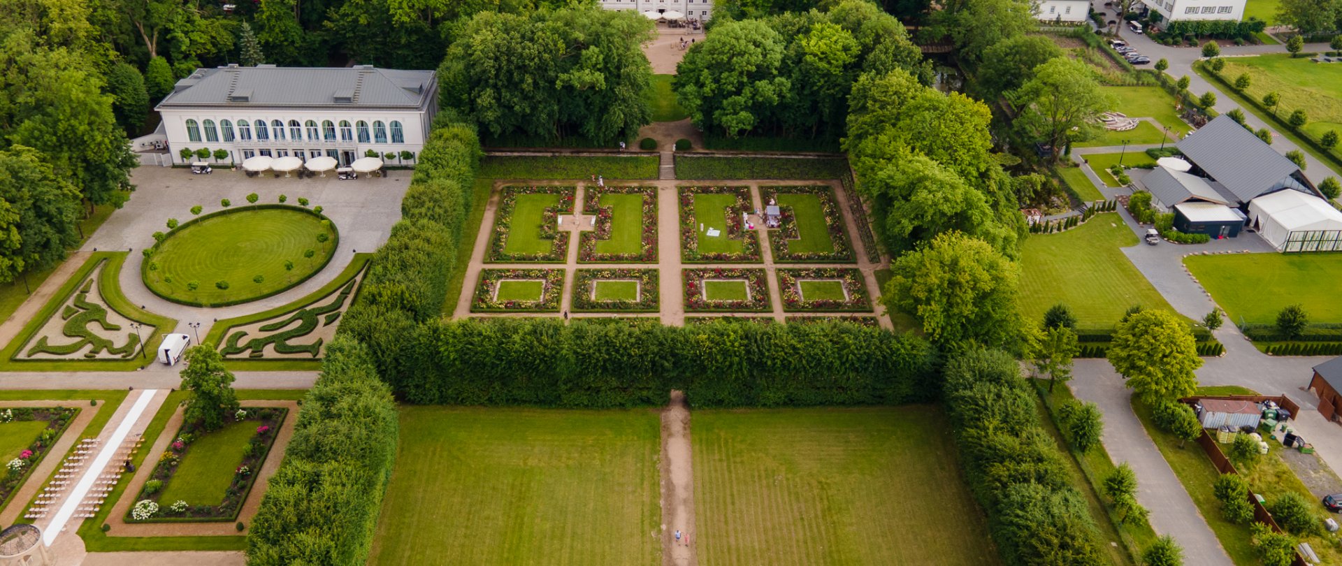 A pyramid stack of empty crystal champagne coupe glasses on a glass table with a dark background and soft lighting.