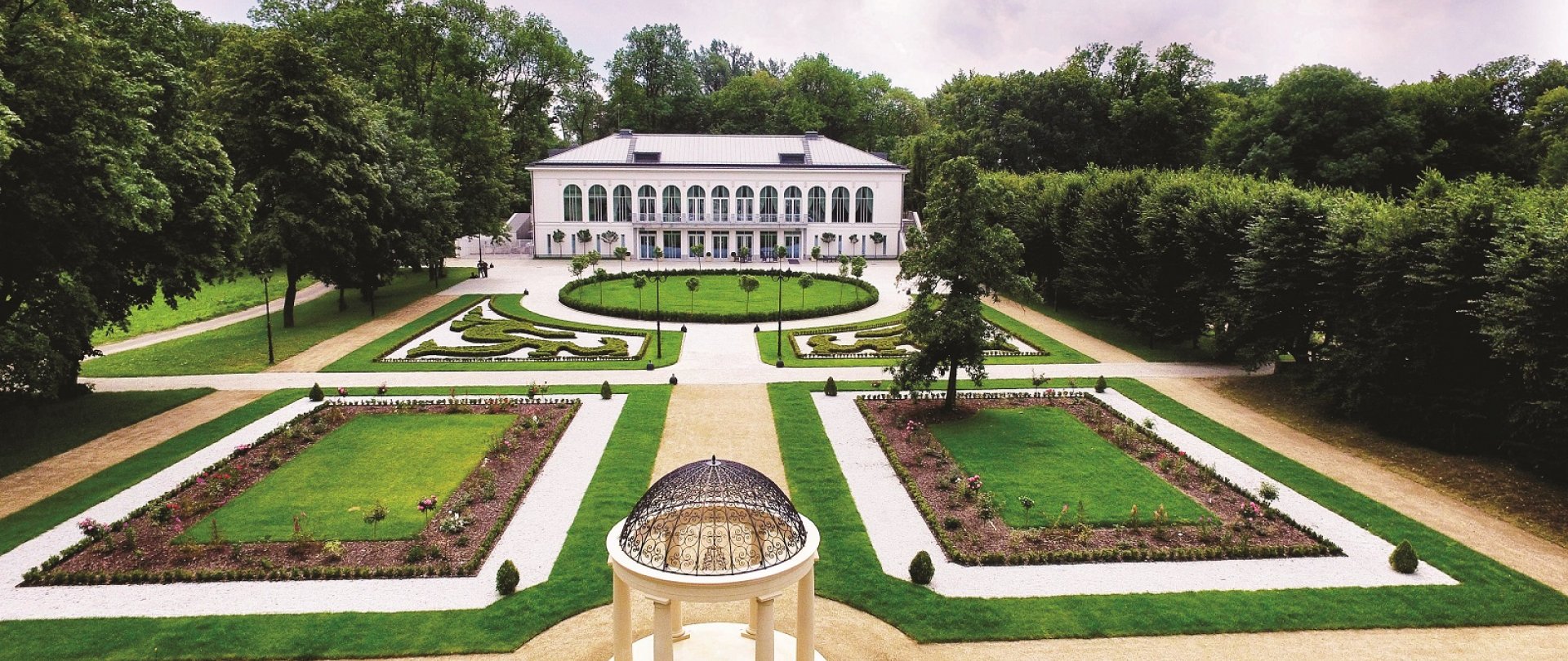 A pyramid stack of empty crystal champagne coupe glasses on a glass table with a dark background and soft lighting.