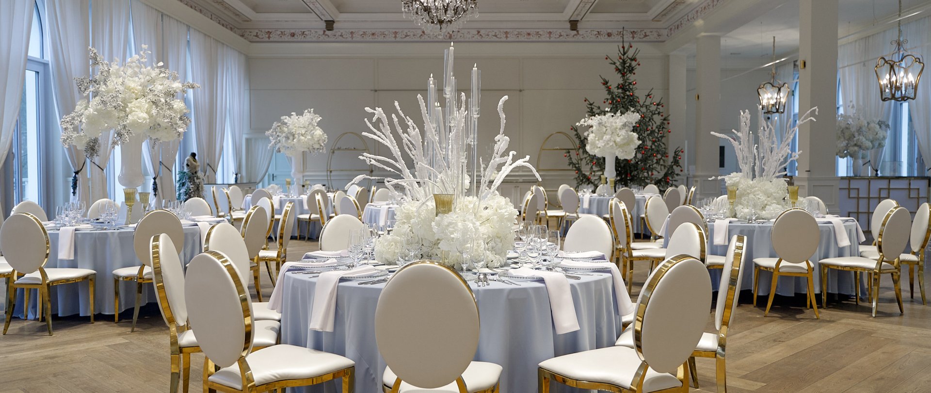 A pyramid stack of empty crystal champagne coupe glasses on a glass table with a dark background and soft lighting.