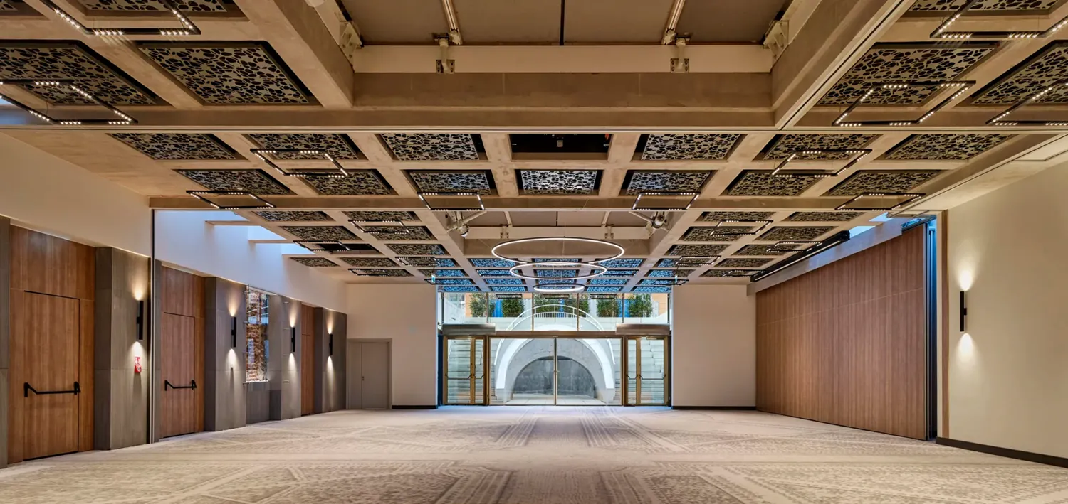 A pyramid stack of empty crystal champagne coupe glasses on a glass table with a dark background and soft lighting.