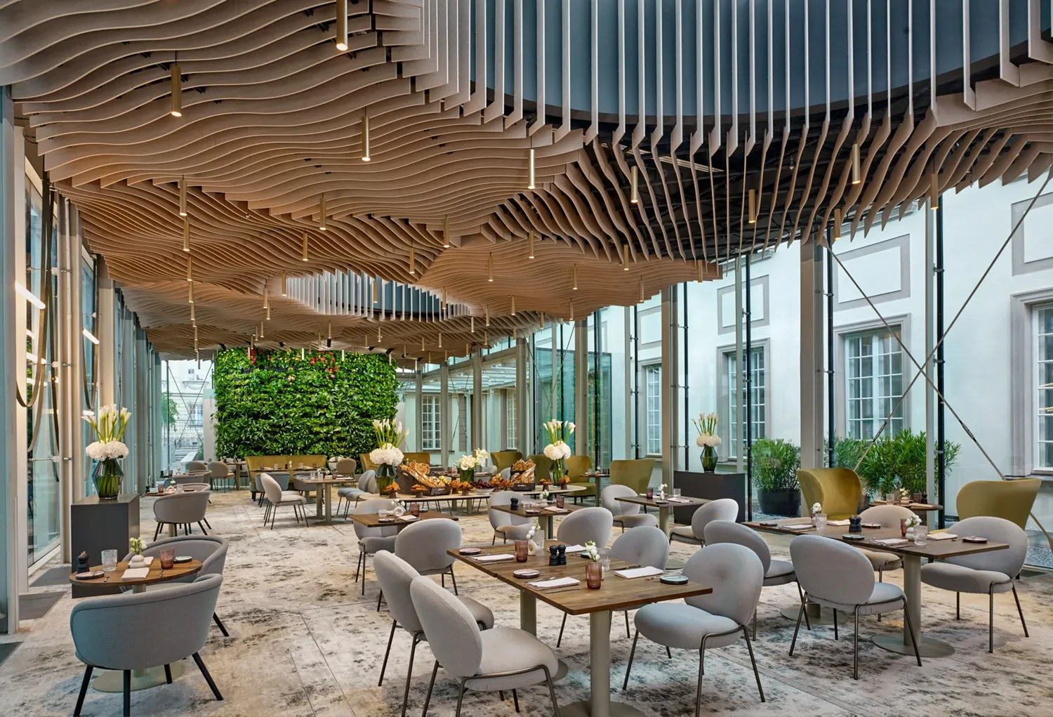 A pyramid stack of empty crystal champagne coupe glasses on a glass table with a dark background and soft lighting.