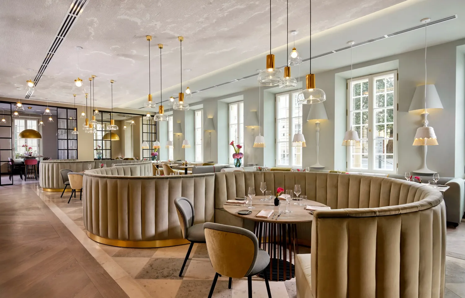 A pyramid stack of empty crystal champagne coupe glasses on a glass table with a dark background and soft lighting.