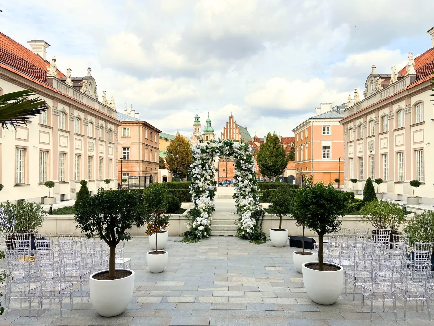 A pyramid stack of empty crystal champagne coupe glasses on a glass table with a dark background and soft lighting.