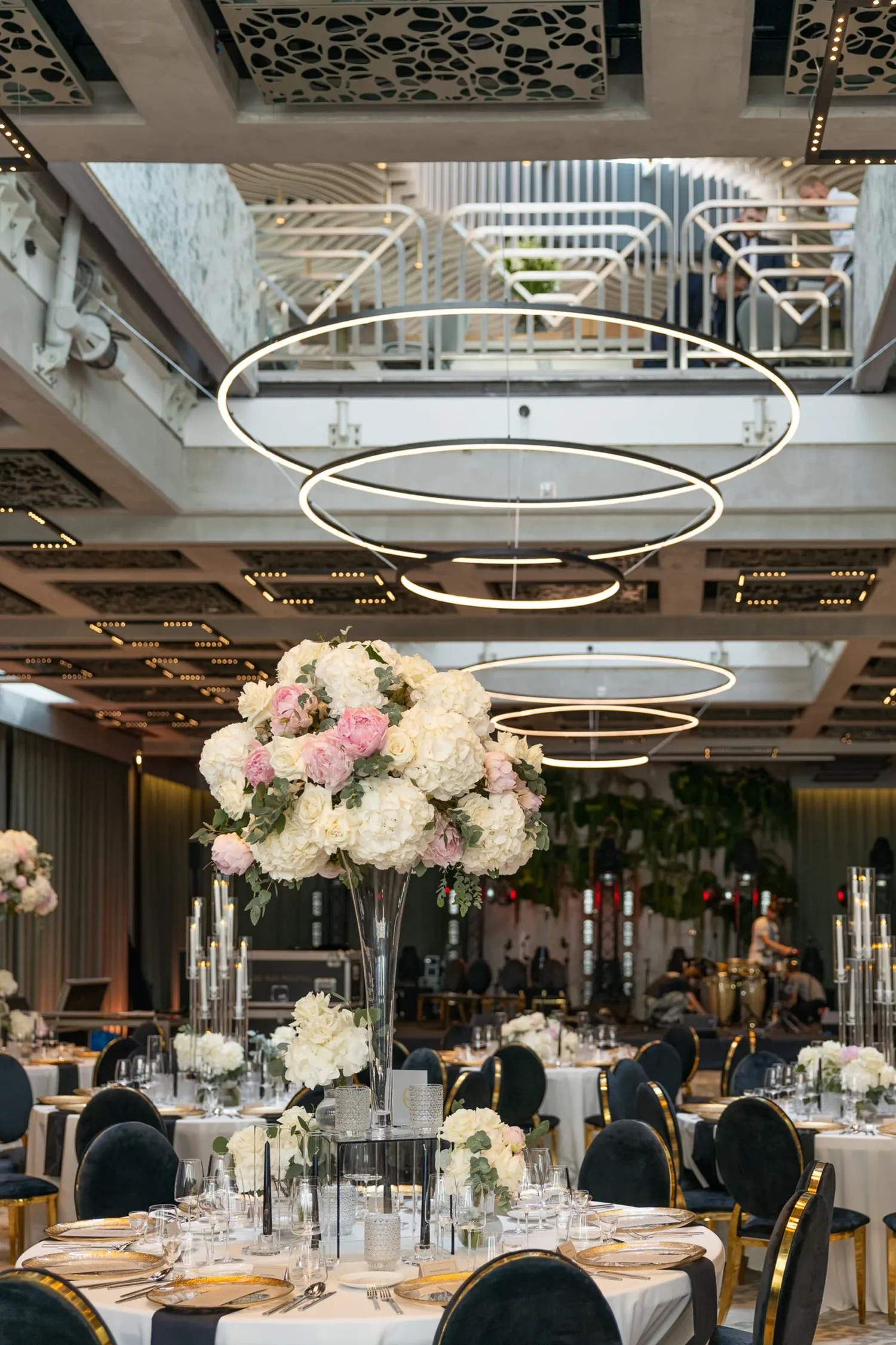 A pyramid stack of empty crystal champagne coupe glasses on a glass table with a dark background and soft lighting.