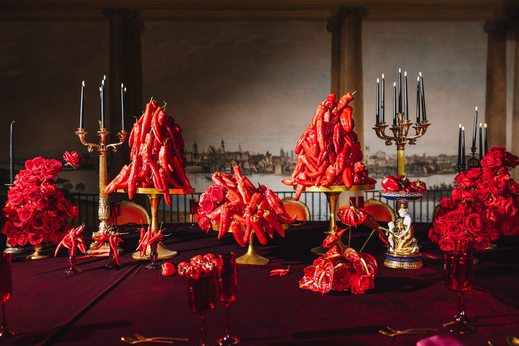 A pyramid stack of empty crystal champagne coupe glasses on a glass table with a dark background and soft lighting.