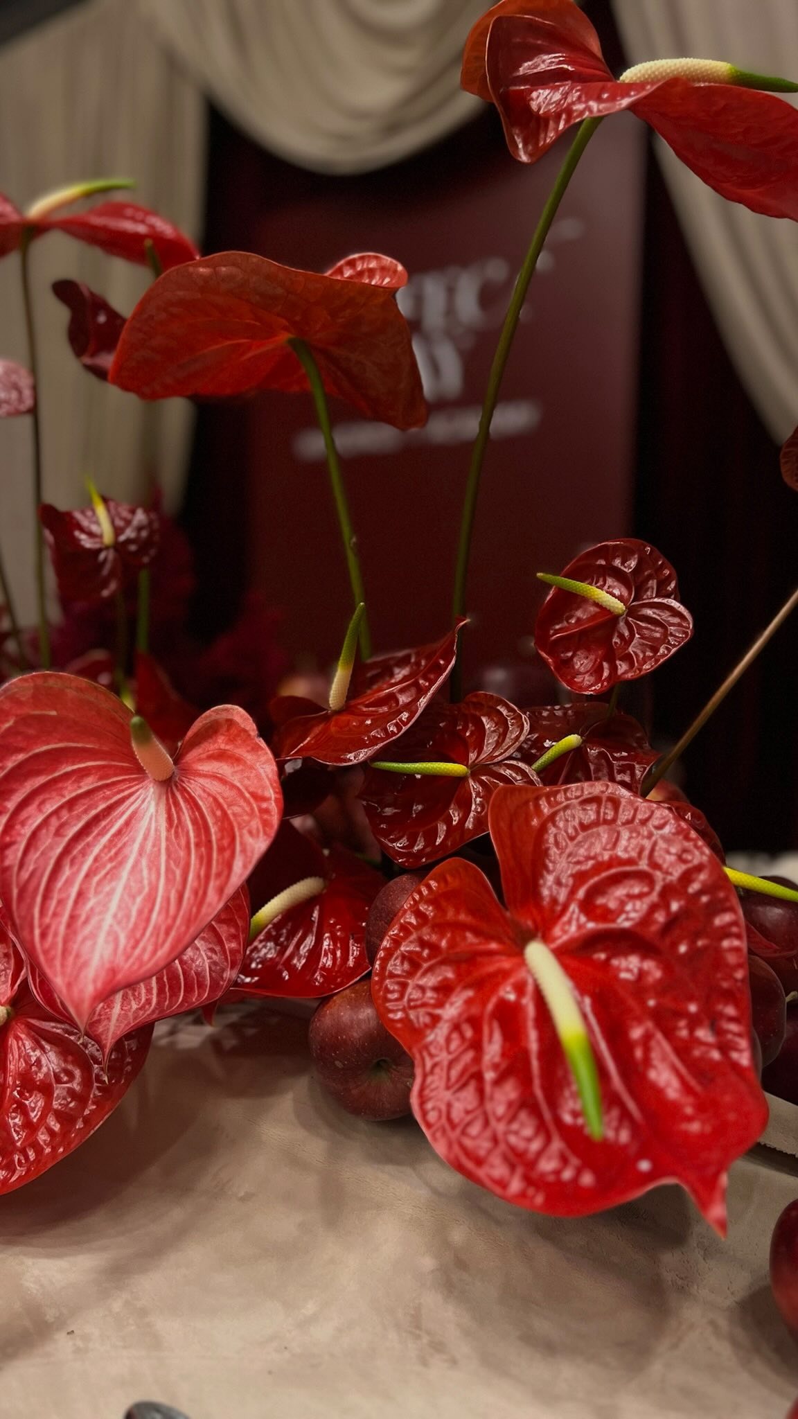 A pyramid stack of empty crystal champagne coupe glasses on a glass table with a dark background and soft lighting.