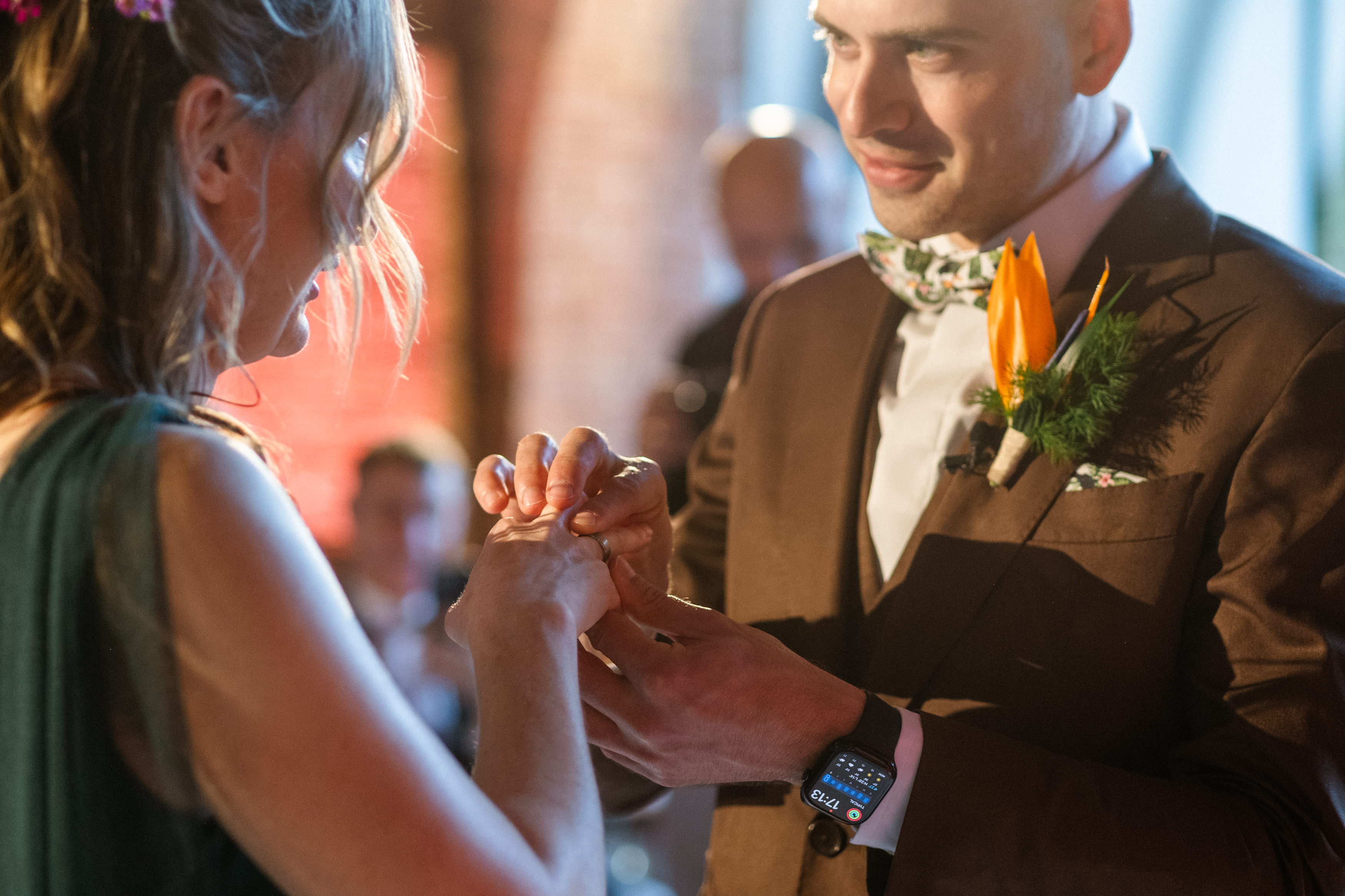 Bride and groom kissing on an ornate balcony under modern cross-shaped ceiling lights.