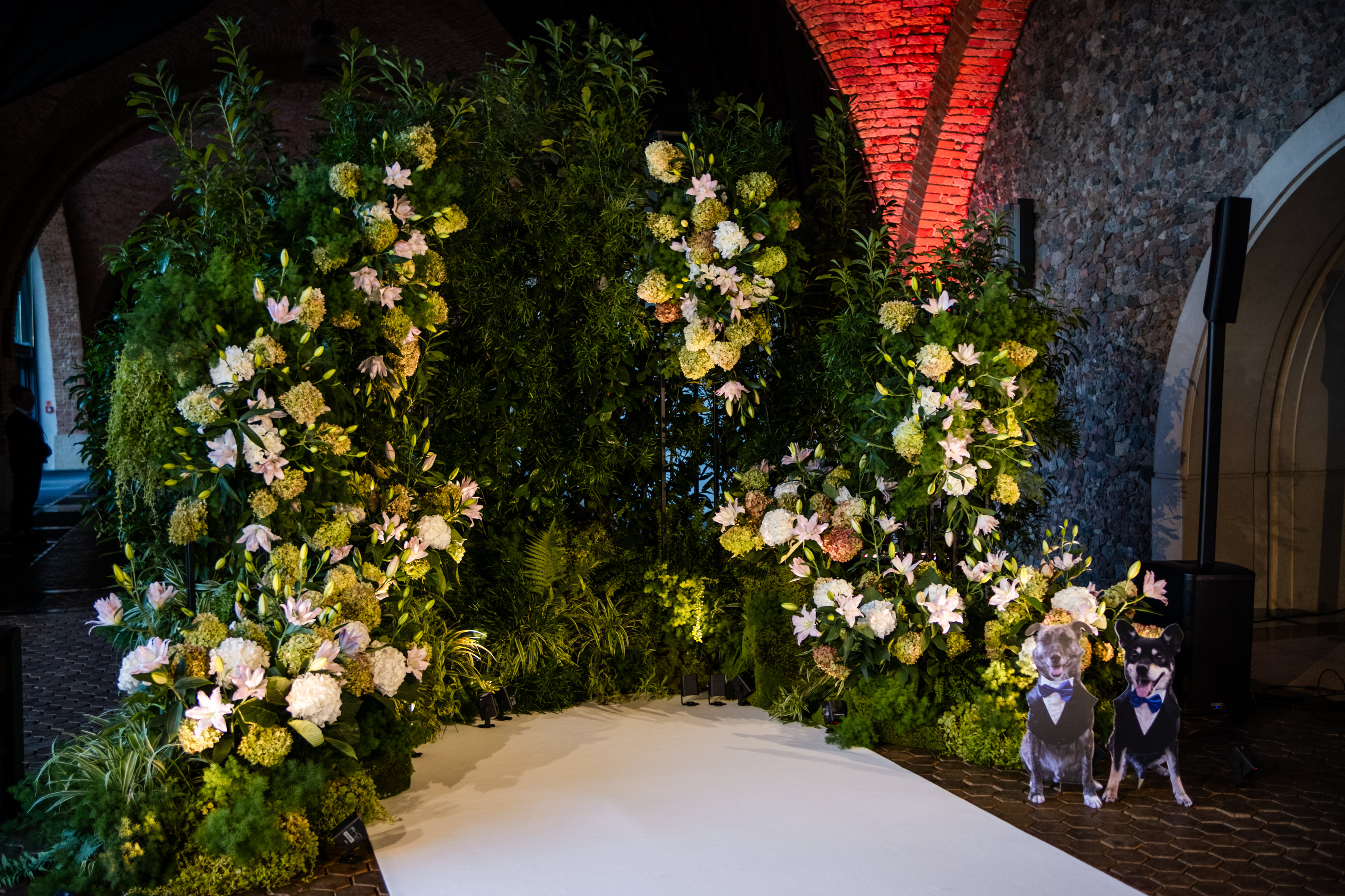 Bride in white dress holding bouquet while an older man in a black suit and bow tie kisses her forehead during a wedding ceremony.