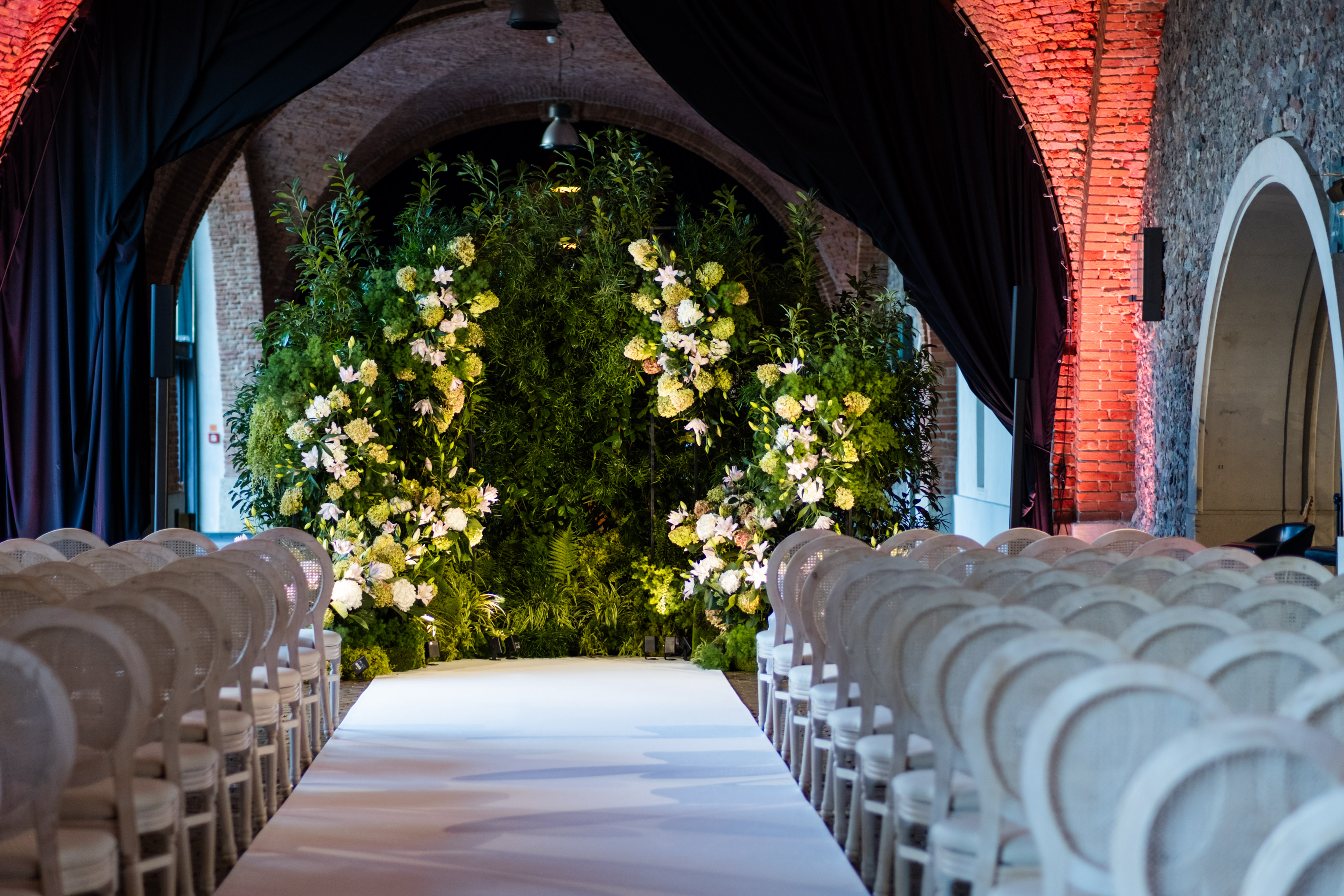 Uniformed men holding swords forming an archway in a decorated church with guests seated on either side.