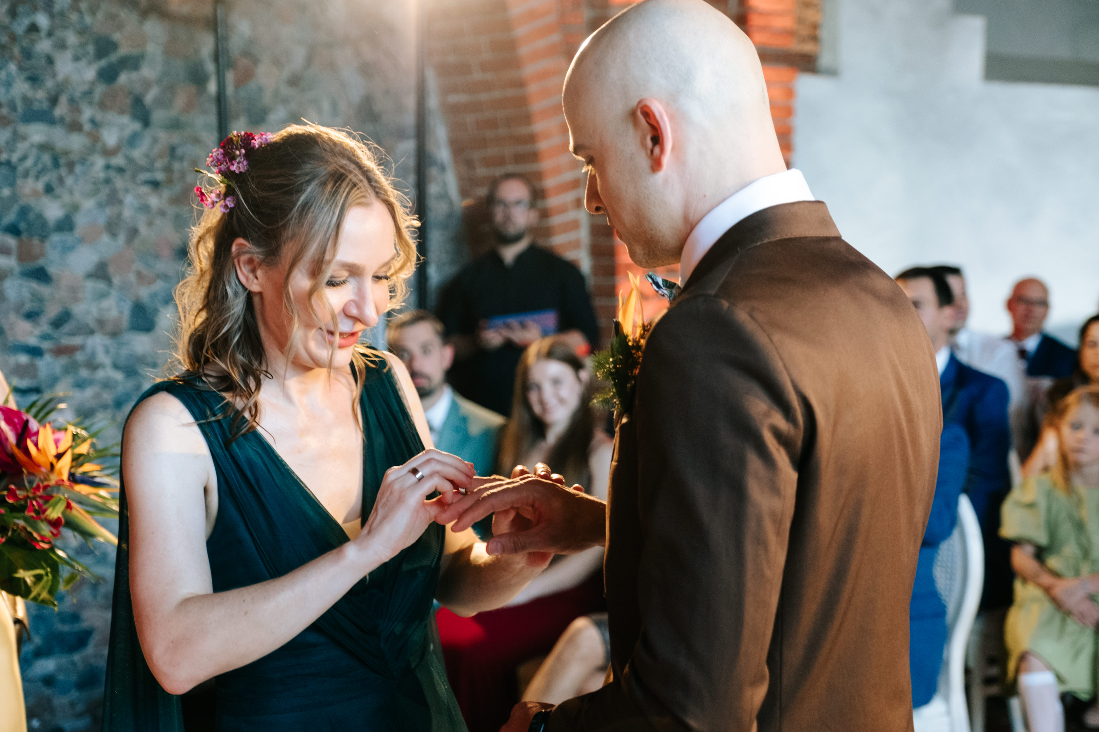 Bride in white dress holding bouquet while an older man in a black suit and bow tie kisses her forehead during a wedding ceremony.