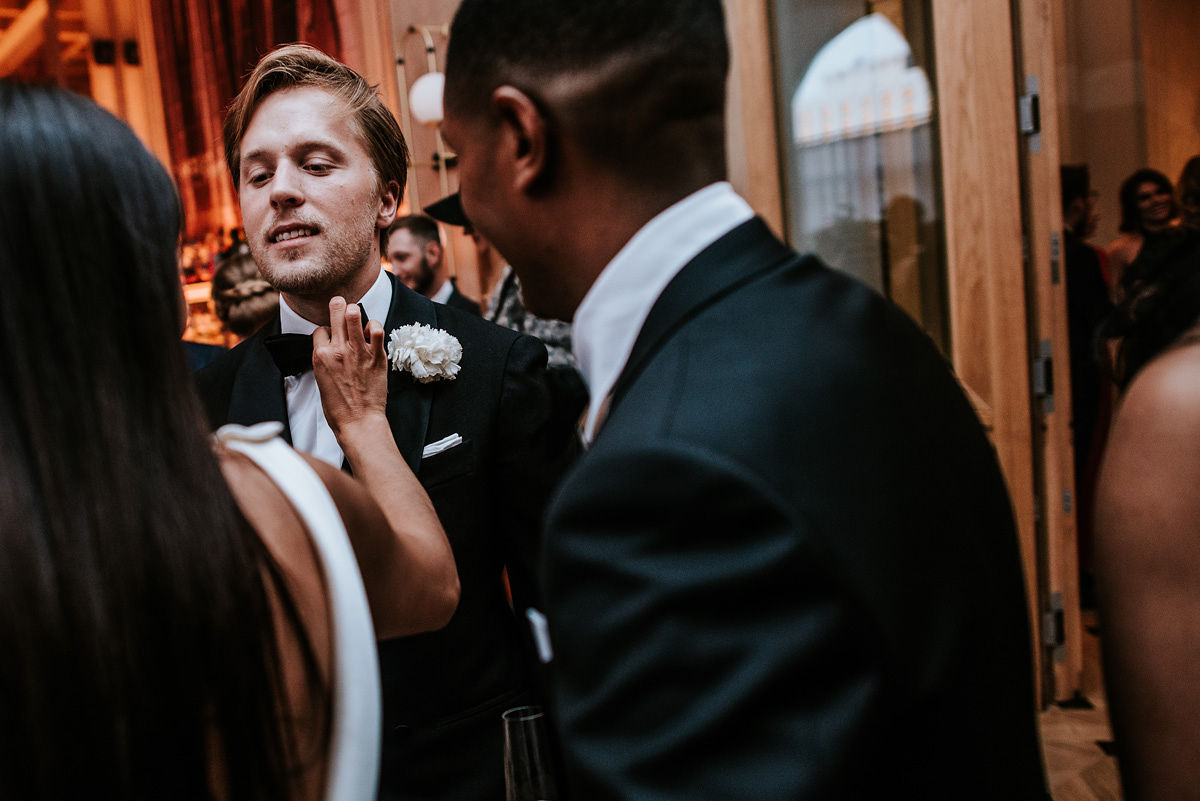 Bride in a white wedding dress and veil sitting in the back seat of a car, looking to the side.