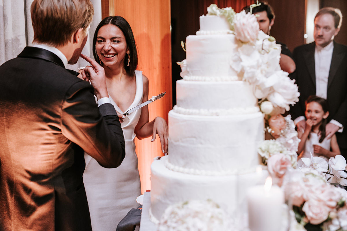 Bride in a white wedding dress and veil sitting in the back seat of a car, looking to the side.