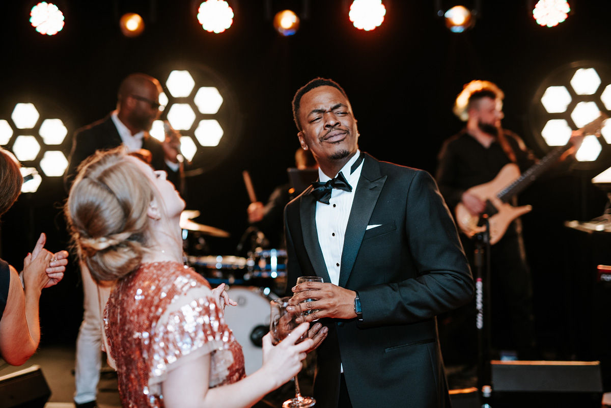 Bride in a white wedding dress and veil sitting in the back seat of a car, looking to the side.
