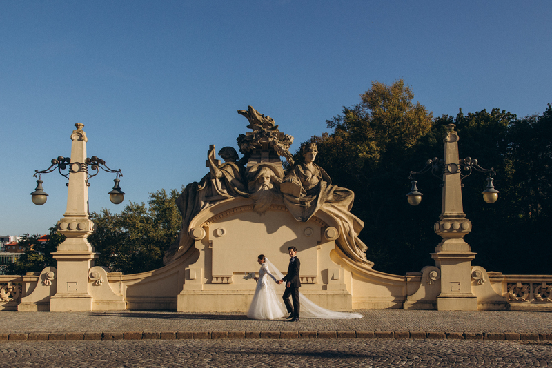 Bride in a lace wedding dress holding a bouquet sitting next to a groom in a dark suit and blue bow tie during a wedding ceremony.