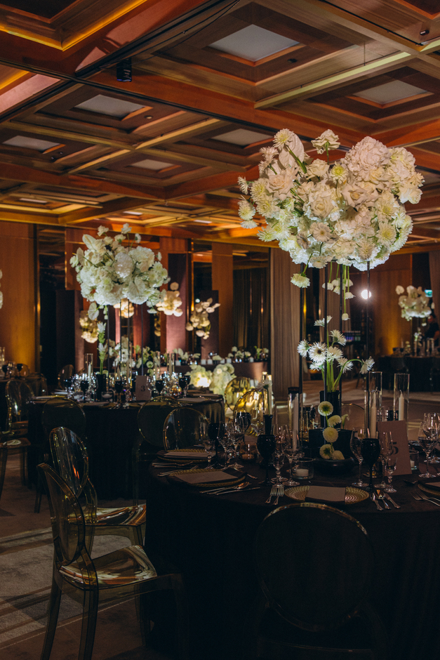 Three people ascending dark stone stairs, one wearing a white lace wedding dress, one in brown shoes and black trousers, and one in burgundy high heels.