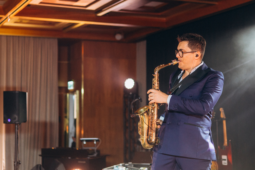 Bride and groom walking arm-in-arm down a white aisle decorated with tall vases of white flowers at an outdoor wedding ceremony.