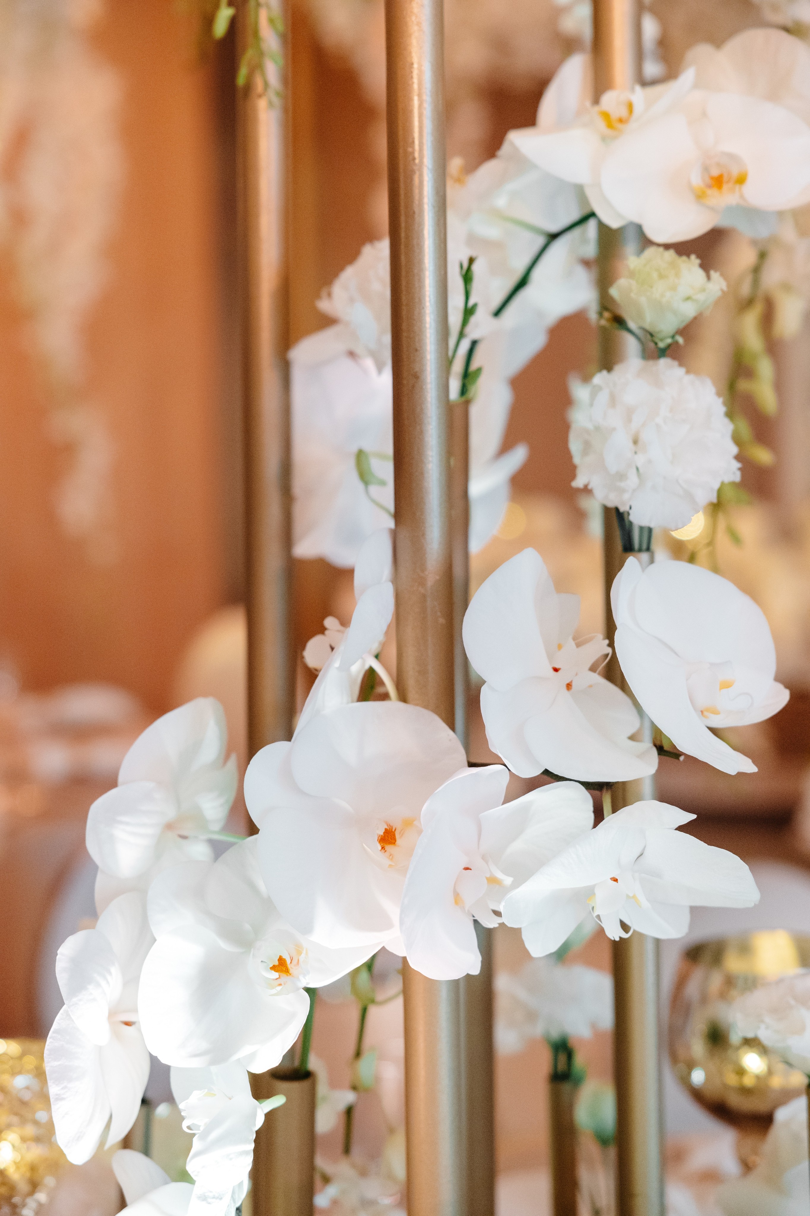 Couple dressed in white standing on a wooden pier overlooking a calm lake surrounded by trees at sunset.