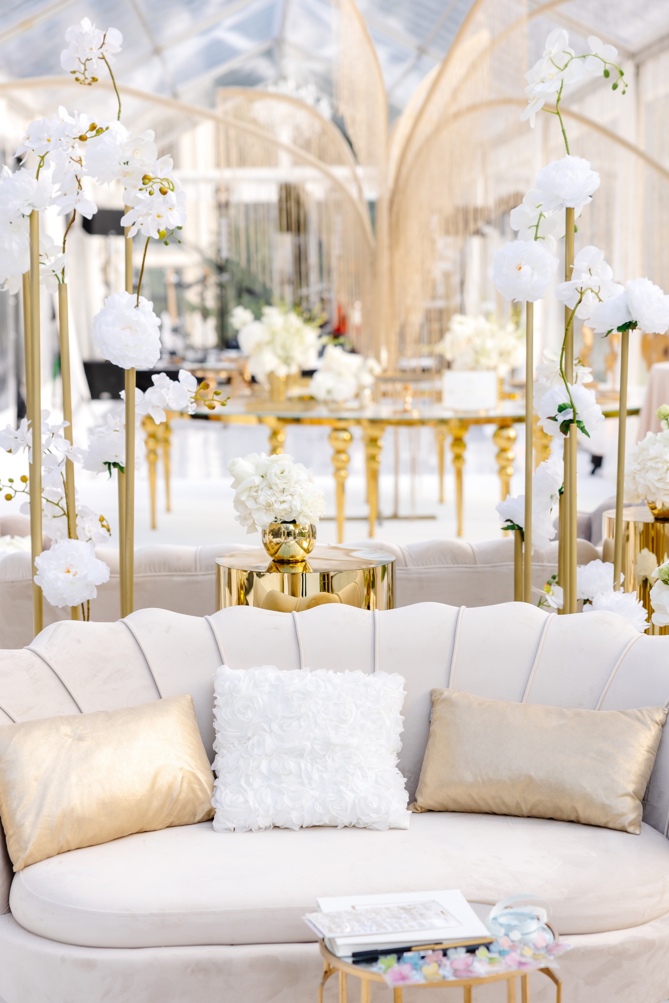 Couple dressed in white standing on a wooden pier overlooking a calm lake surrounded by trees at sunset.