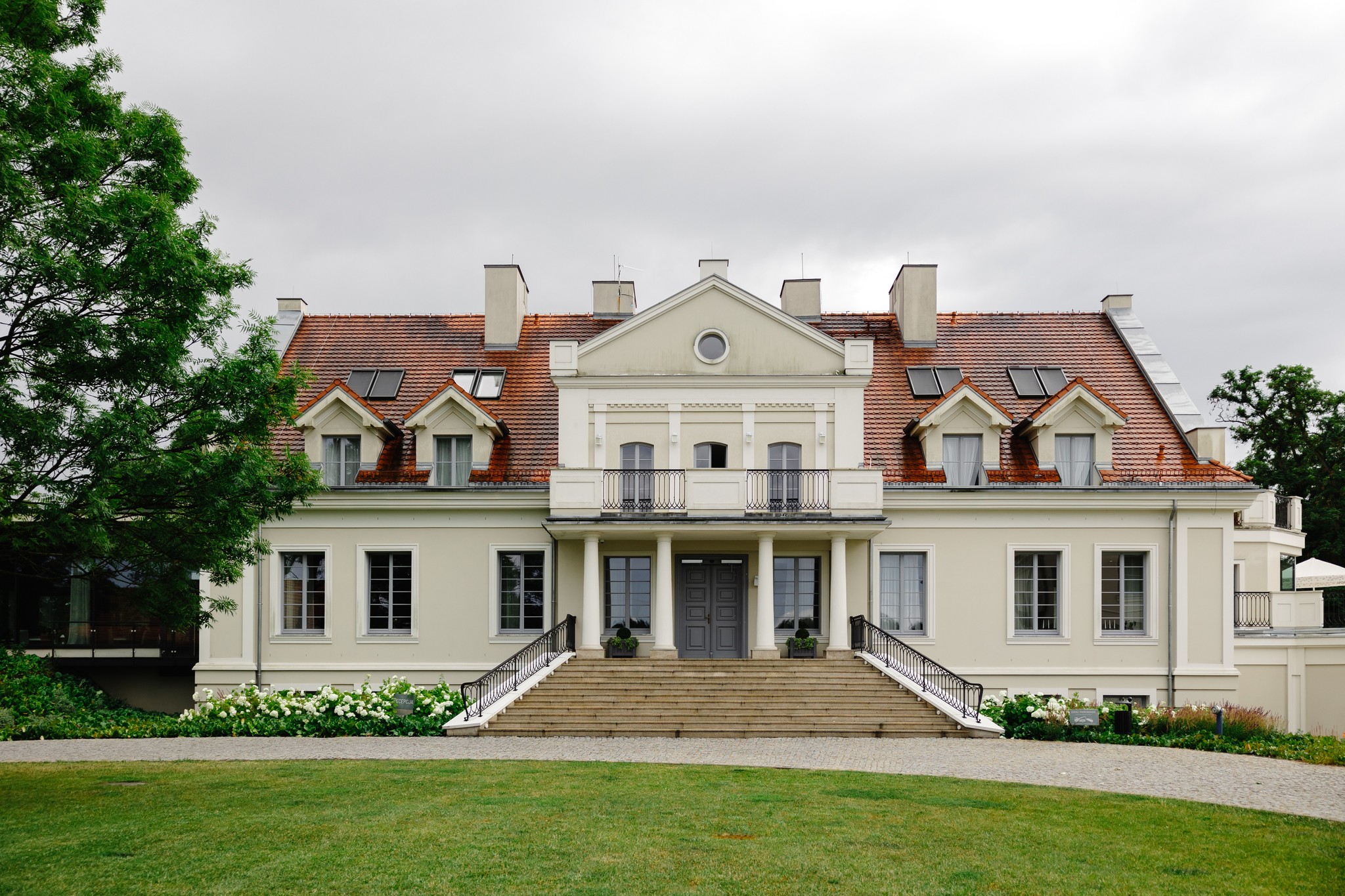 Bride and groom standing under a floral canopy exchanging vows at an outdoor wedding ceremony with seated guests watching.