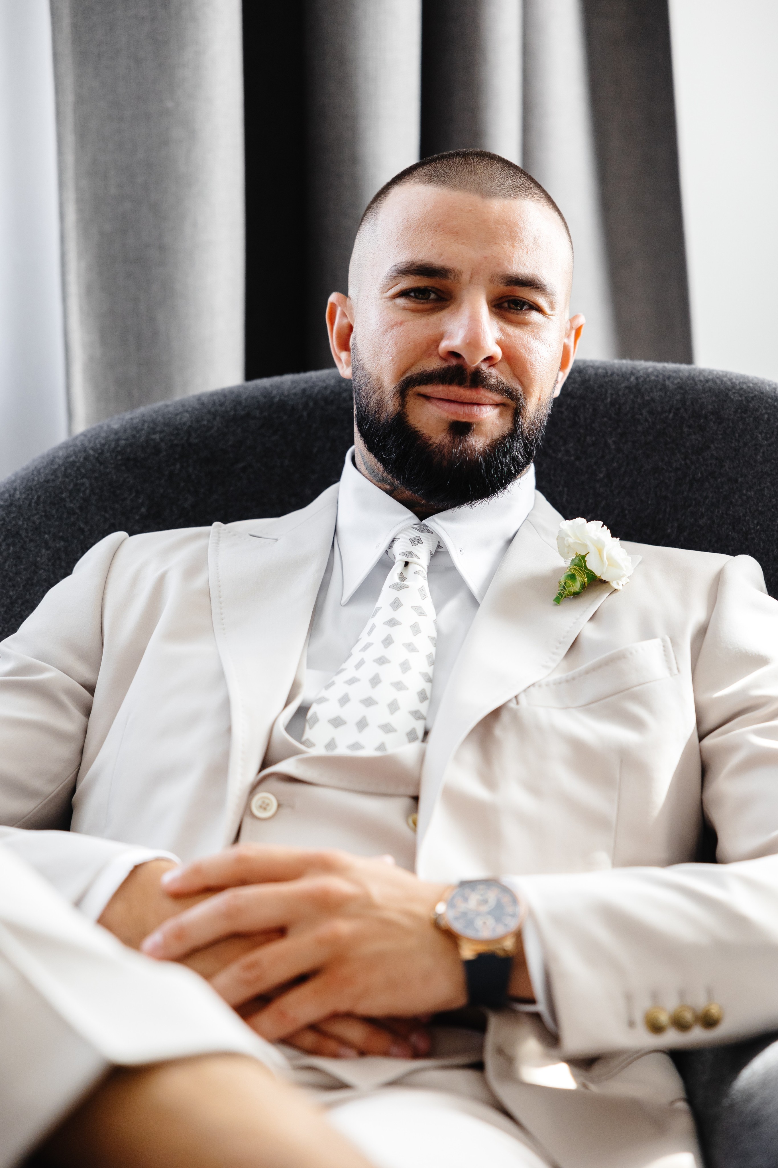 Bride and groom dressed in white sharing a kiss outdoors at night near a multi-tiered wedding cake.