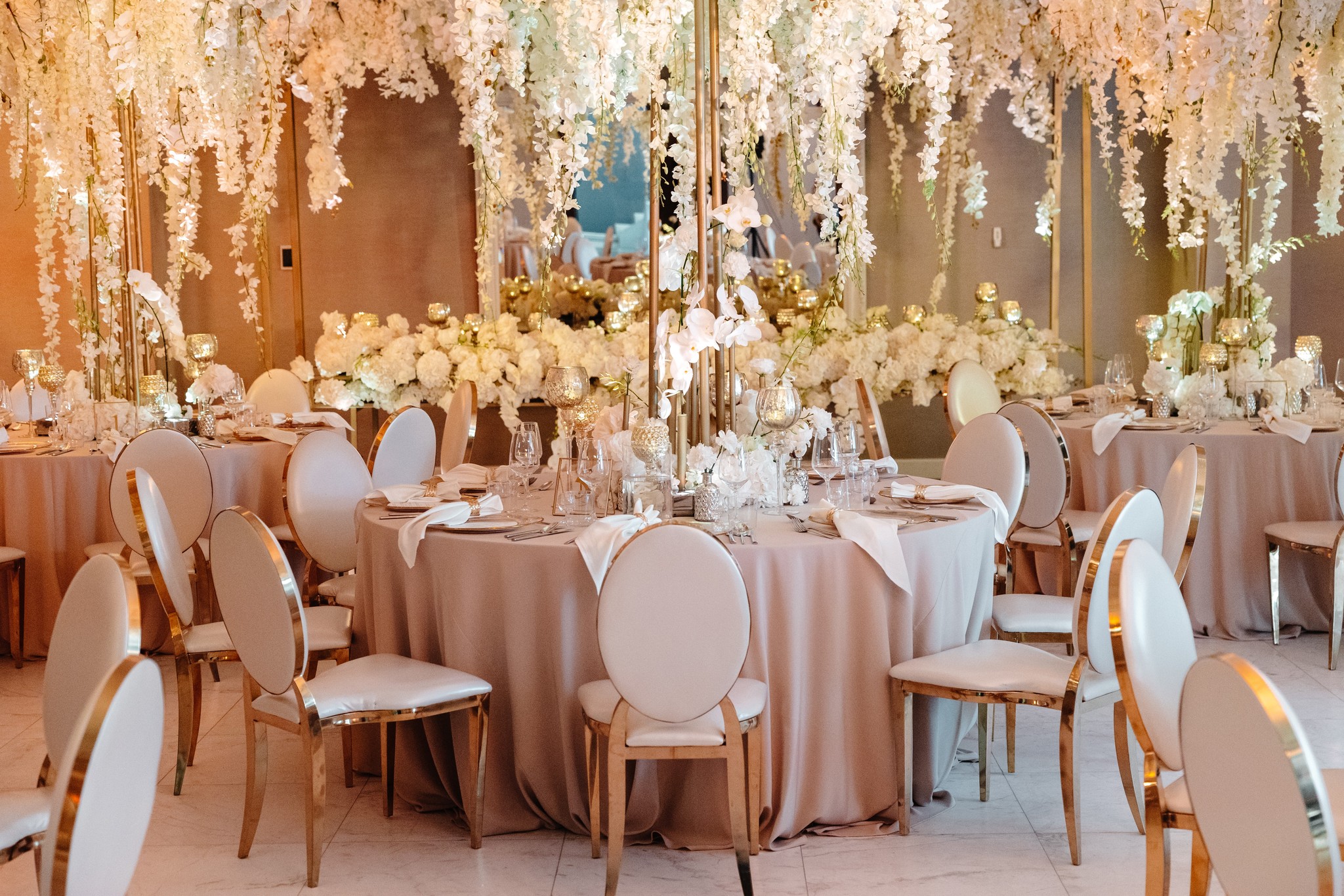 Bride and groom standing under a floral canopy exchanging vows at an outdoor wedding ceremony with seated guests watching.