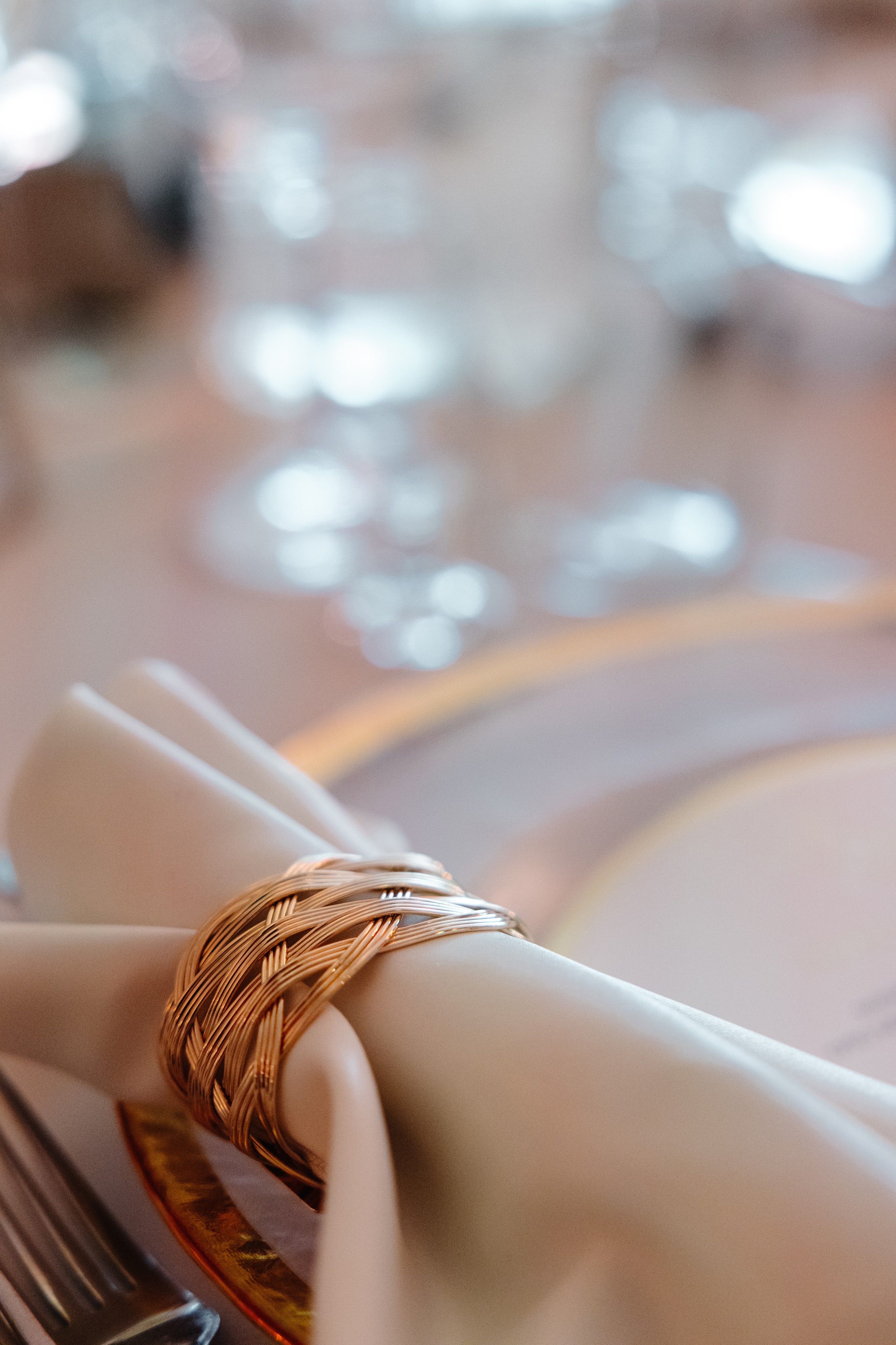 Couple dressed in white standing on a wooden pier overlooking a calm lake surrounded by trees at sunset.