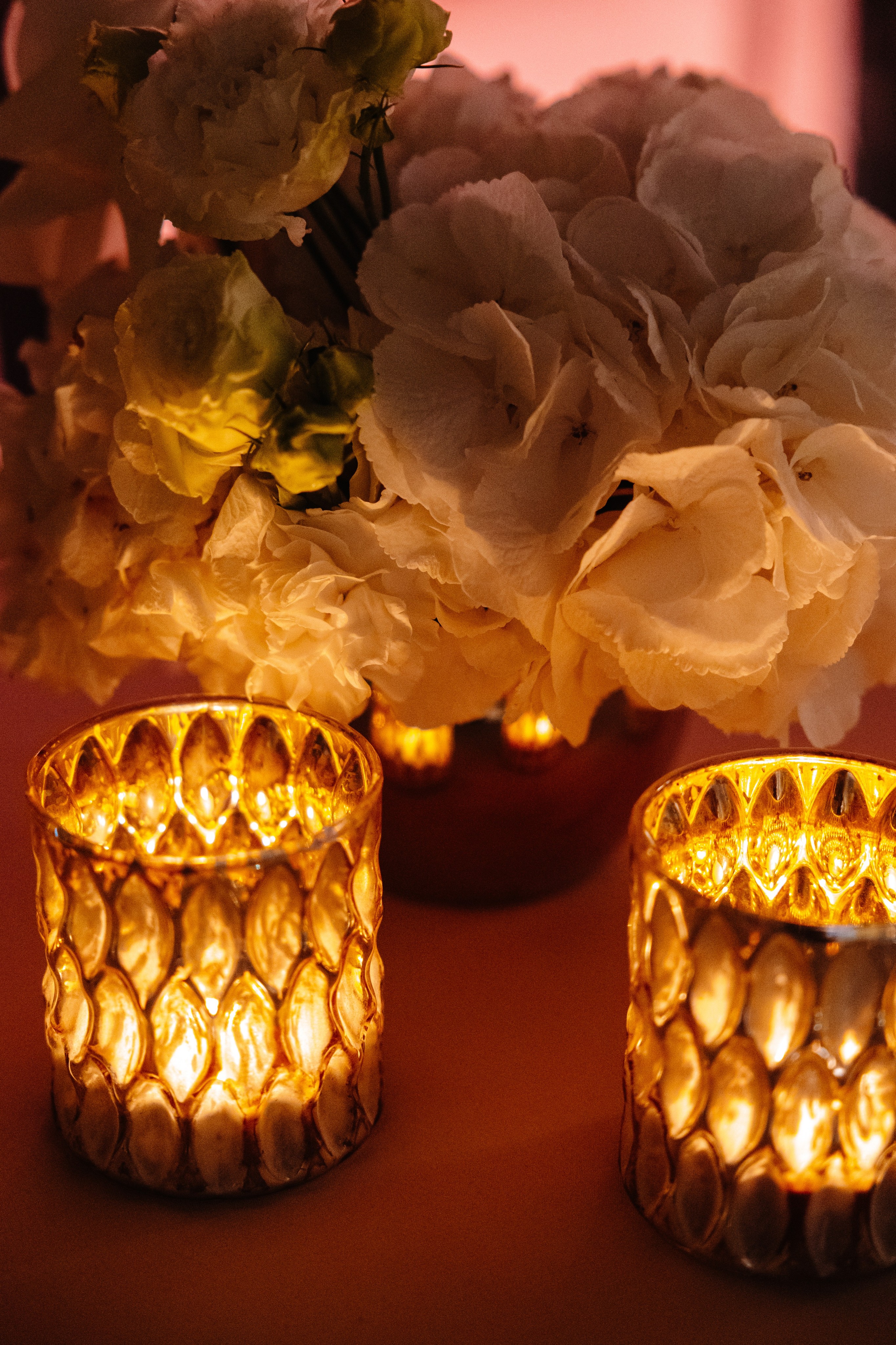 Bride and groom standing under a floral canopy exchanging vows at an outdoor wedding ceremony with seated guests watching.