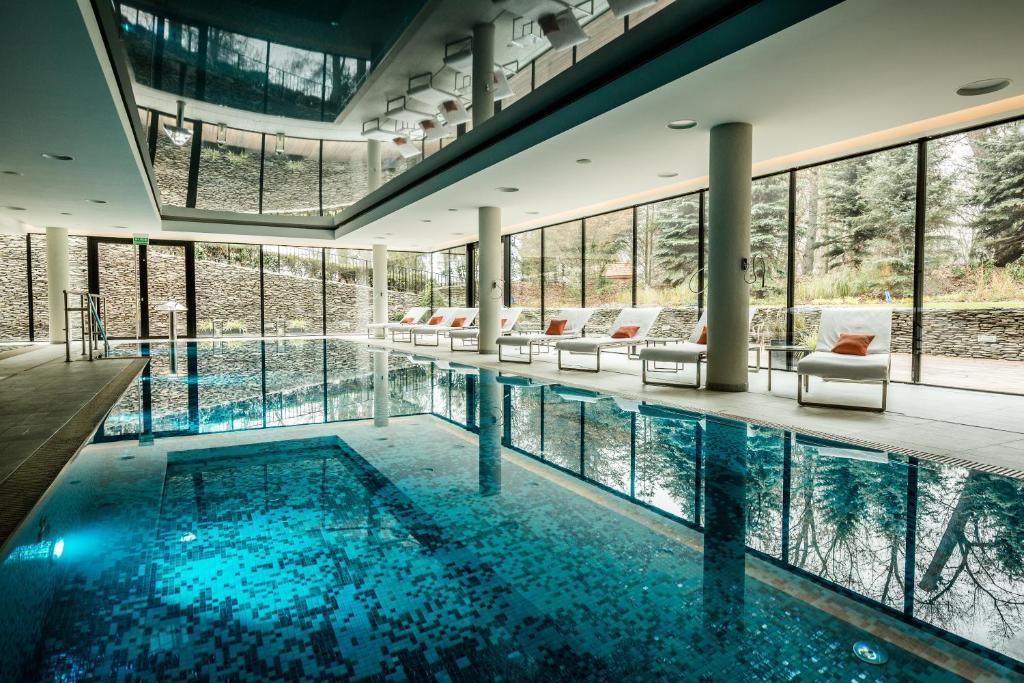 A pyramid stack of empty crystal champagne coupe glasses on a glass table with a dark background and soft lighting.