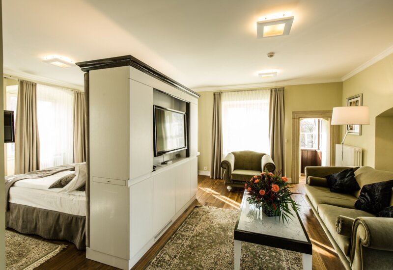 A pyramid stack of empty crystal champagne coupe glasses on a glass table with a dark background and soft lighting.