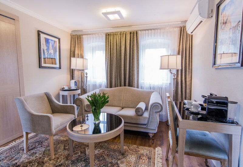A pyramid stack of empty crystal champagne coupe glasses on a glass table with a dark background and soft lighting.