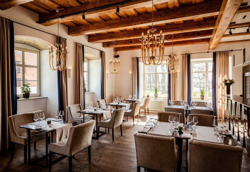 A pyramid stack of empty crystal champagne coupe glasses on a glass table with a dark background and soft lighting.