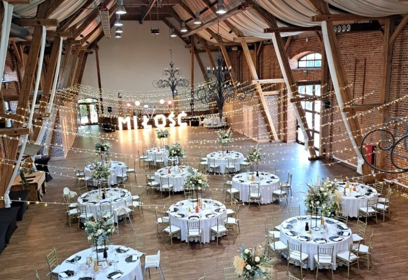 A pyramid stack of empty crystal champagne coupe glasses on a glass table with a dark background and soft lighting.