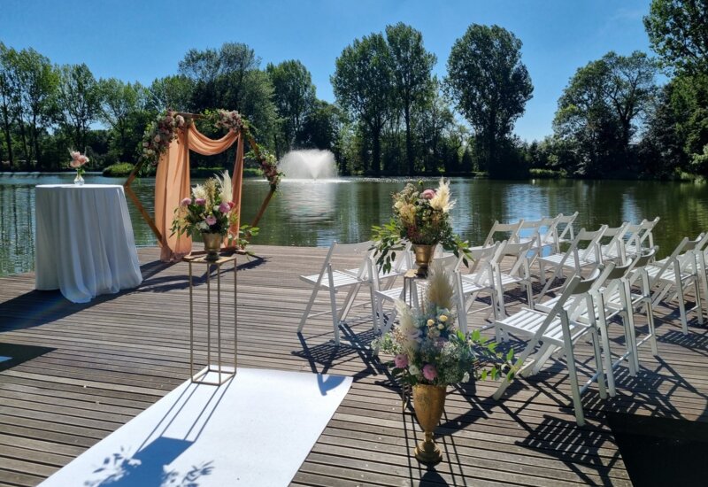 A pyramid stack of empty crystal champagne coupe glasses on a glass table with a dark background and soft lighting.