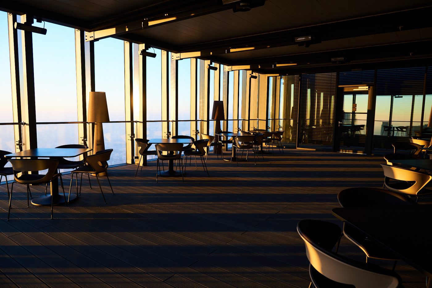 A pyramid stack of empty crystal champagne coupe glasses on a glass table with a dark background and soft lighting.