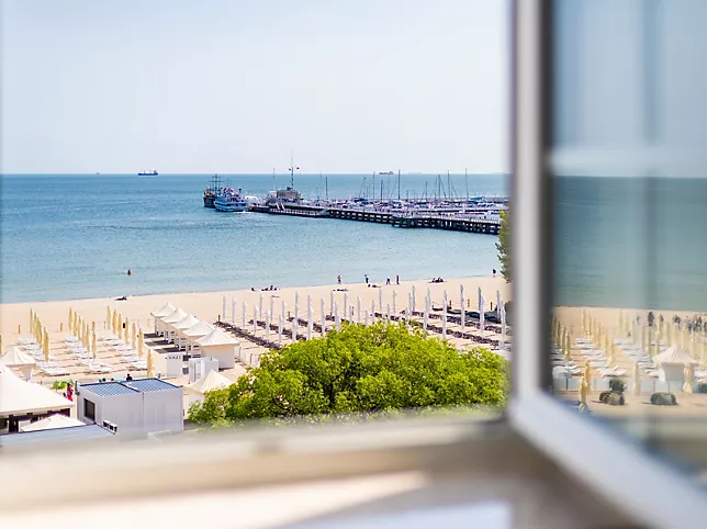 A pyramid stack of empty crystal champagne coupe glasses on a glass table with a dark background and soft lighting.